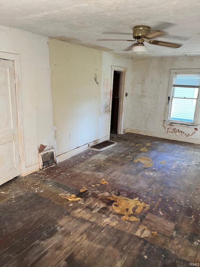 spare room featuring dark wood-type flooring, a textured ceiling, and ceiling fan