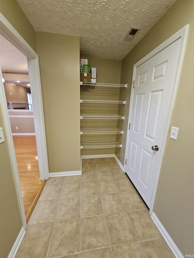 hall with a textured ceiling and light wood-type flooring