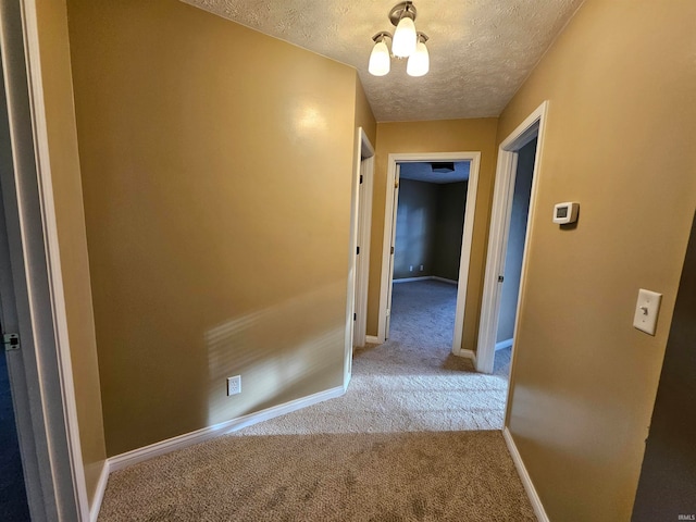 hallway featuring a textured ceiling and light colored carpet