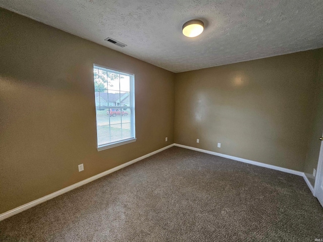 carpeted empty room featuring a textured ceiling