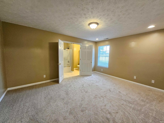 unfurnished bedroom with ensuite bathroom, a textured ceiling, and carpet floors