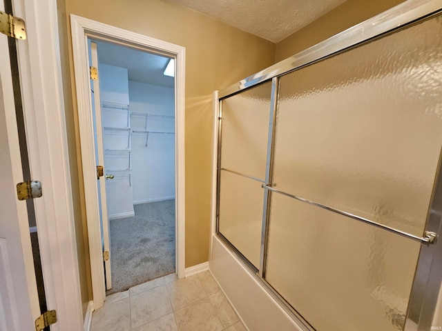 bathroom with shower / bath combination with glass door, a textured ceiling, and tile patterned floors