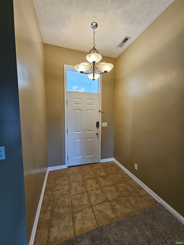 foyer featuring a textured ceiling and dark colored carpet