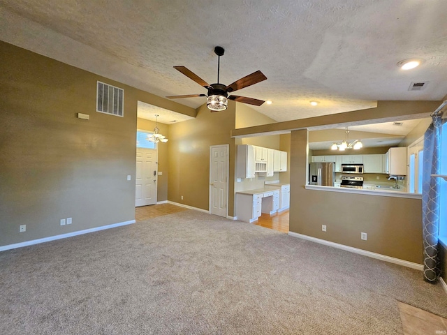 unfurnished living room featuring ceiling fan with notable chandelier, light carpet, lofted ceiling, and a textured ceiling