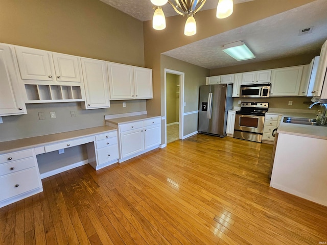 kitchen with stainless steel appliances, sink, light wood-type flooring, and white cabinets