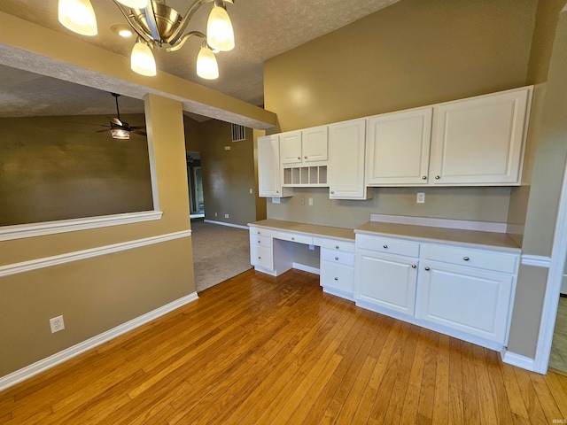 kitchen with lofted ceiling, white cabinets, ceiling fan with notable chandelier, and light hardwood / wood-style floors