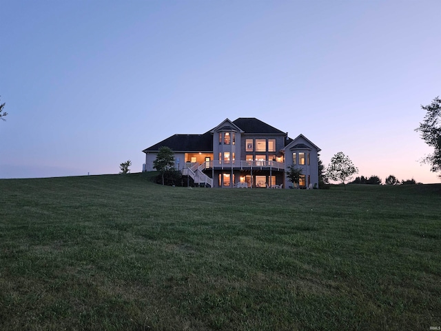 back house at dusk featuring a yard and a wooden deck