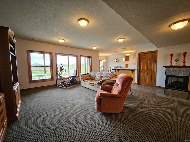 living room featuring a textured ceiling, a tiled fireplace, and dark colored carpet