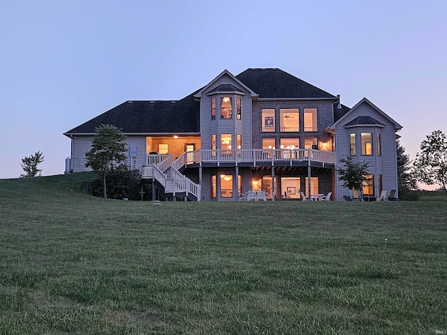 back house at dusk with a yard and a deck