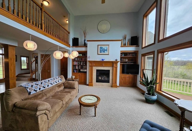 carpeted living room with plenty of natural light, a fireplace, and a towering ceiling