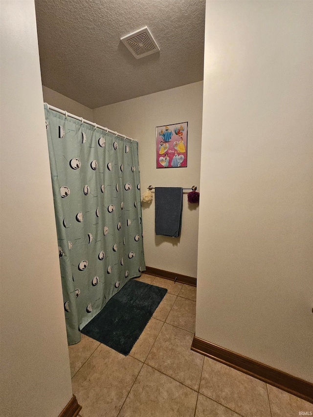 bathroom featuring tile patterned flooring and a textured ceiling