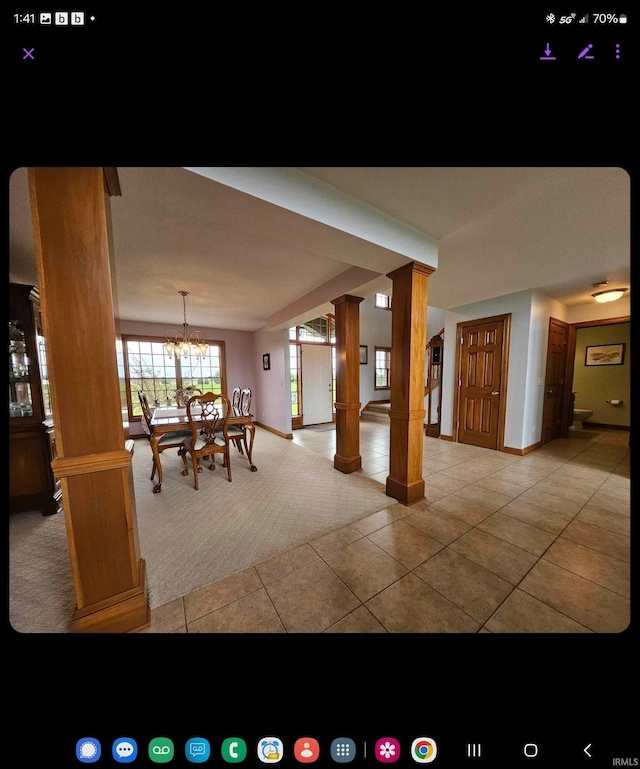 unfurnished dining area featuring tile patterned floors, a chandelier, and ornate columns