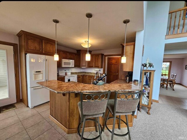 kitchen with a textured ceiling, decorative light fixtures, stainless steel refrigerator with ice dispenser, a kitchen bar, and kitchen peninsula