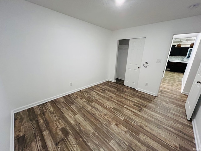 unfurnished bedroom with dark hardwood / wood-style flooring and a closet