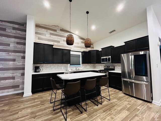 kitchen with light hardwood / wood-style flooring, a center island, stainless steel appliances, and vaulted ceiling