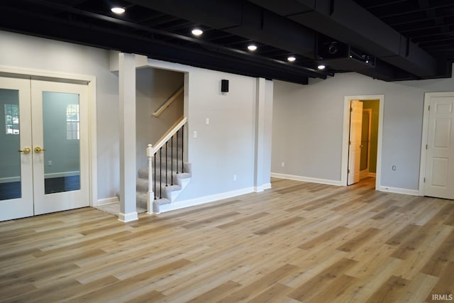 basement with french doors and light hardwood / wood-style floors