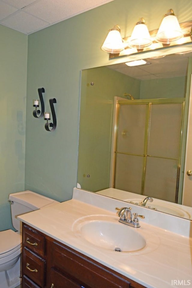 bathroom featuring vanity, toilet, a paneled ceiling, and a shower with shower door