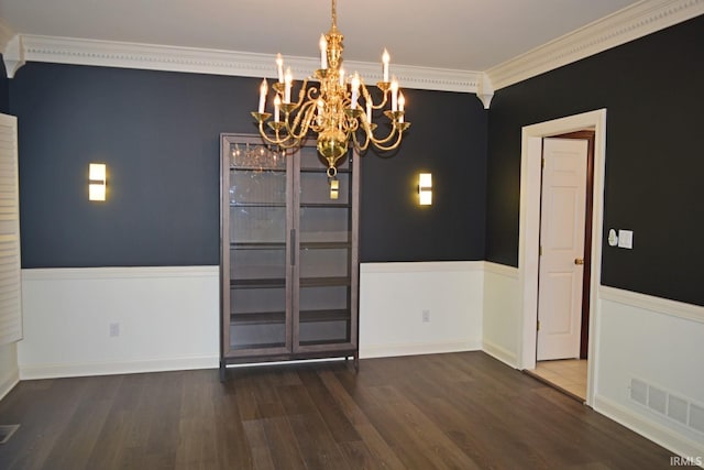 unfurnished dining area featuring dark wood-type flooring, a notable chandelier, and crown molding