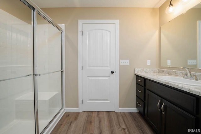 bathroom with a shower with door, hardwood / wood-style flooring, and vanity