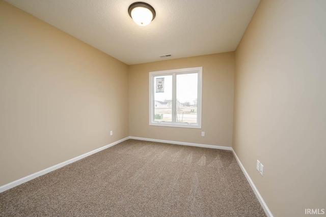 empty room with carpet floors and a textured ceiling