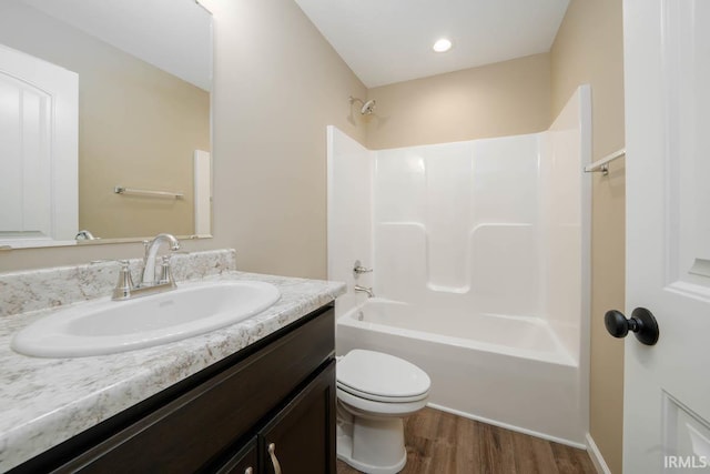 full bathroom with wood-type flooring, shower / washtub combination, vanity, and toilet