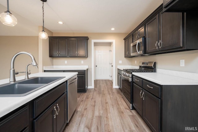 kitchen with dark brown cabinetry, hanging light fixtures, sink, light hardwood / wood-style flooring, and appliances with stainless steel finishes