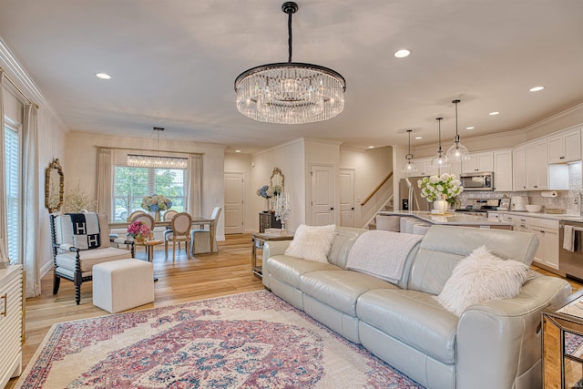 living room with crown molding, light hardwood / wood-style flooring, and an inviting chandelier