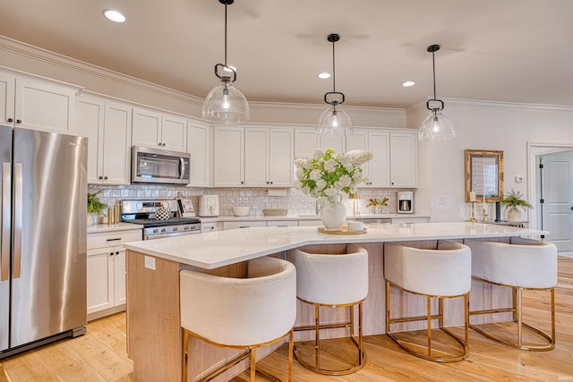 kitchen featuring a kitchen island, pendant lighting, appliances with stainless steel finishes, light wood-type flooring, and white cabinets