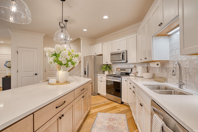 kitchen featuring ornamental molding, sink, appliances with stainless steel finishes, light brown cabinets, and light hardwood / wood-style floors