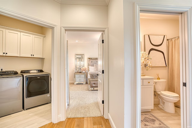 laundry room featuring crown molding, cabinets, separate washer and dryer, and light hardwood / wood-style floors