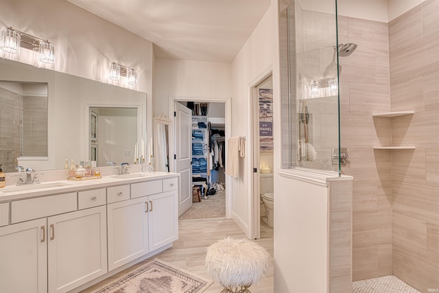 bathroom with vanity, toilet, and a tile shower