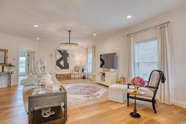 living room featuring ornamental molding, light hardwood / wood-style flooring, and a notable chandelier