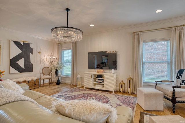 living room with a notable chandelier, plenty of natural light, ornamental molding, and light hardwood / wood-style flooring