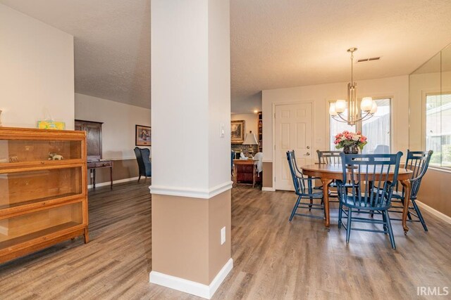 dining area featuring hardwood / wood-style flooring, a chandelier, and a textured ceiling