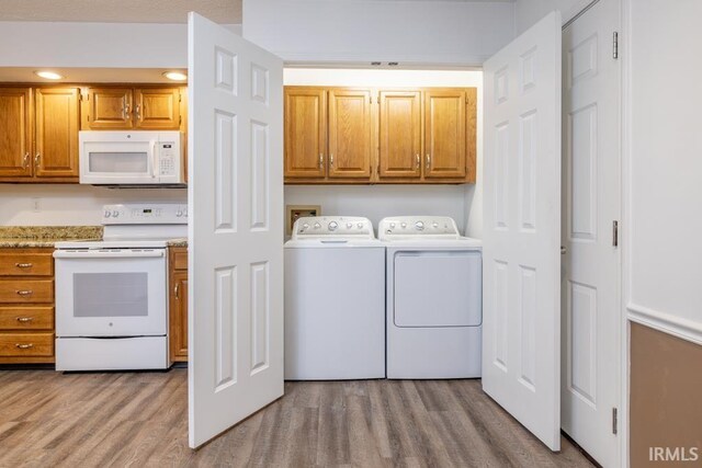 washroom with light wood-type flooring, cabinets, and washer and clothes dryer