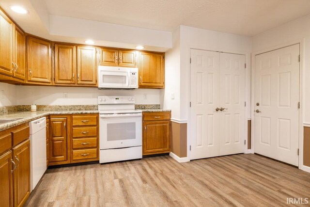 kitchen featuring white appliances, light stone countertops, and light hardwood / wood-style floors