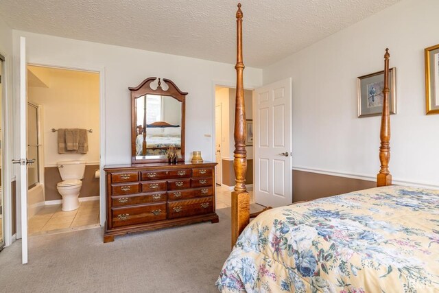 carpeted bedroom featuring a textured ceiling and ensuite bathroom