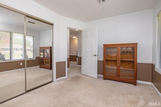 carpeted bedroom with a textured ceiling and a closet