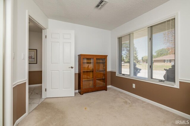 carpeted spare room featuring a textured ceiling and lofted ceiling