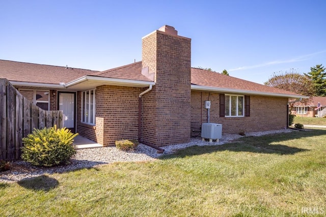 rear view of property featuring a yard, roof with shingles, a chimney, and brick siding