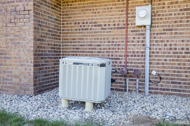 exterior details with electric meter, brick siding, and central AC unit