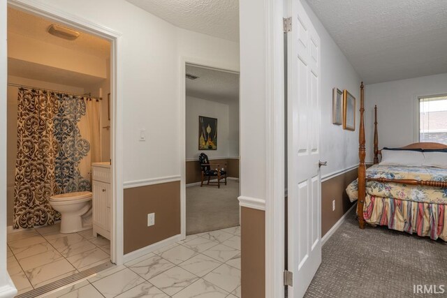 carpeted bedroom featuring a textured ceiling and connected bathroom