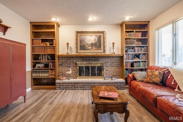 living room featuring hardwood / wood-style flooring, a textured ceiling, and a brick fireplace