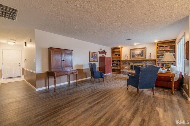 living room with a fireplace, a textured ceiling, built in features, and hardwood / wood-style floors