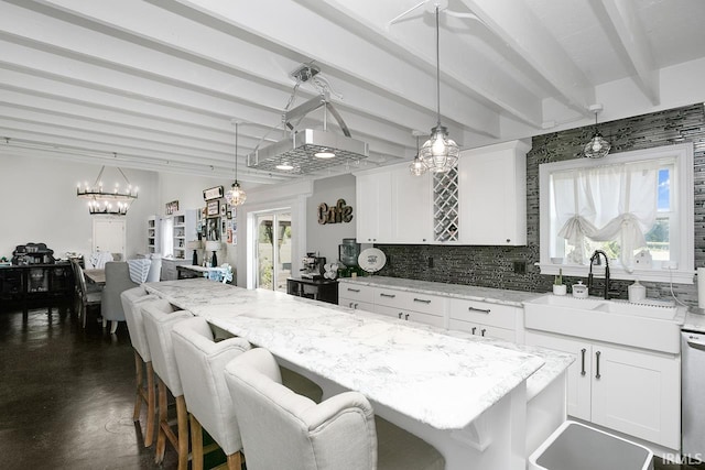 kitchen featuring a breakfast bar, light stone counters, beamed ceiling, and white cabinetry