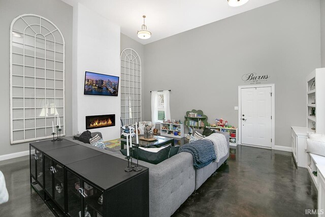 16084 County Road 20, Goshen, IN 46528 - living room featuring a warm lit fireplace, a towering ceiling, baseboards, and concrete floors
