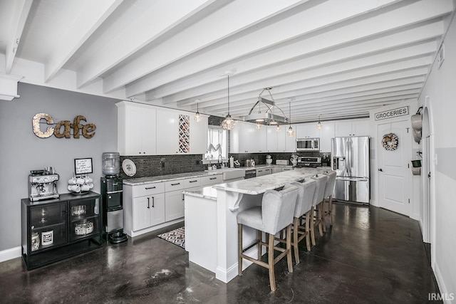 kitchen with decorative light fixtures, stainless steel appliances, a kitchen island, beam ceiling, and white cabinets