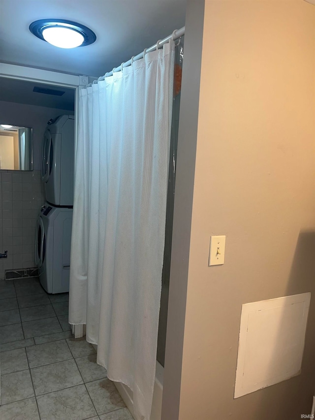 bathroom featuring a shower with curtain, stacked washer and clothes dryer, and tile patterned floors