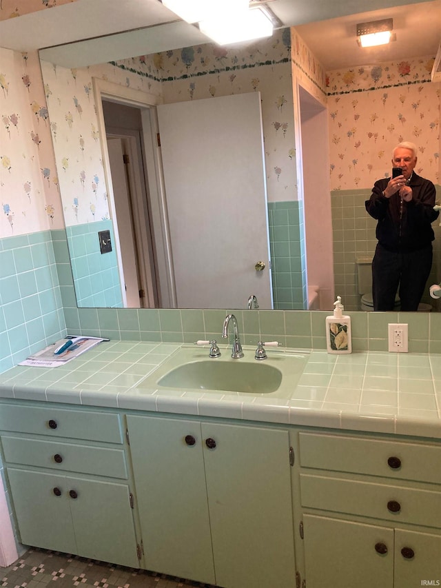 bathroom featuring tile patterned floors, vanity, backsplash, and tile walls