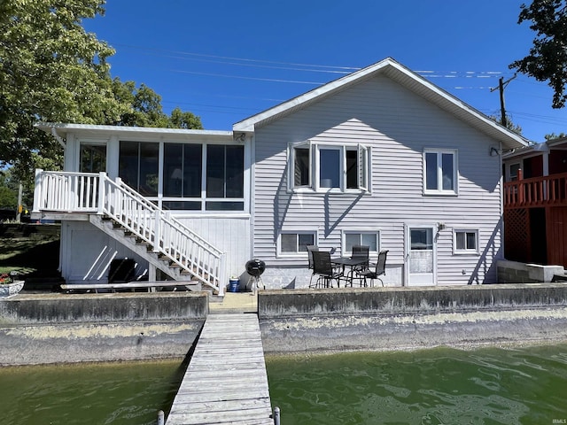 back of house with a water view, a sunroom, and stairs